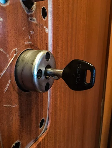 Schließzylinder mit eingestecktem Schlüssel an einer Holztür